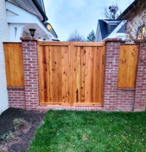 custom wood gate built between brick wall