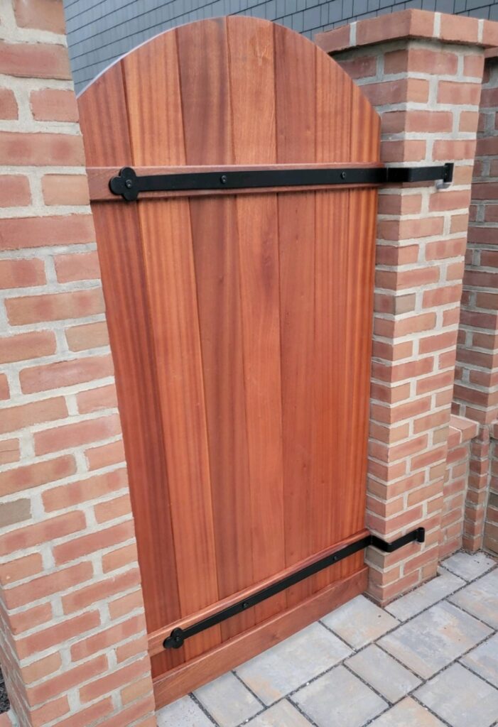 custom wood gate between brick pillars