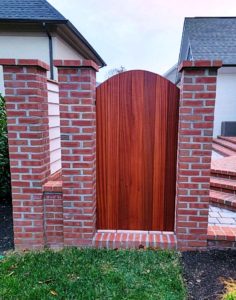 custom wood gate positioned between brick pillars