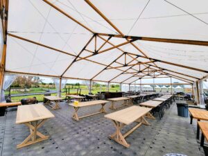 collection of pale custom wood table underneath an outdoor event venue pavilion
