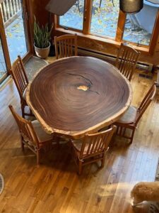 custom round wood slap table surrounded by wood chairs