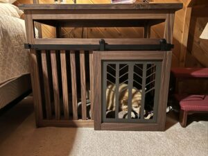 custom dark wood end table with a built-in dog crate beside bed with dog sleeping inside